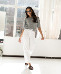 Cropped jeans, light wash, worn by a woman walking in a bright studio.