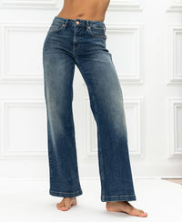 Blue vintage wide leg jeans displayed against a white paneled background.