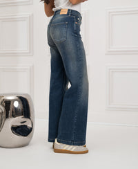 Wide leg blue vintage jeans by Les Deux, shown indoors near a reflective silver stool.