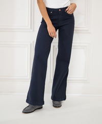 Person wearing dark blue LES DEUX jeans against a white paneled wall.