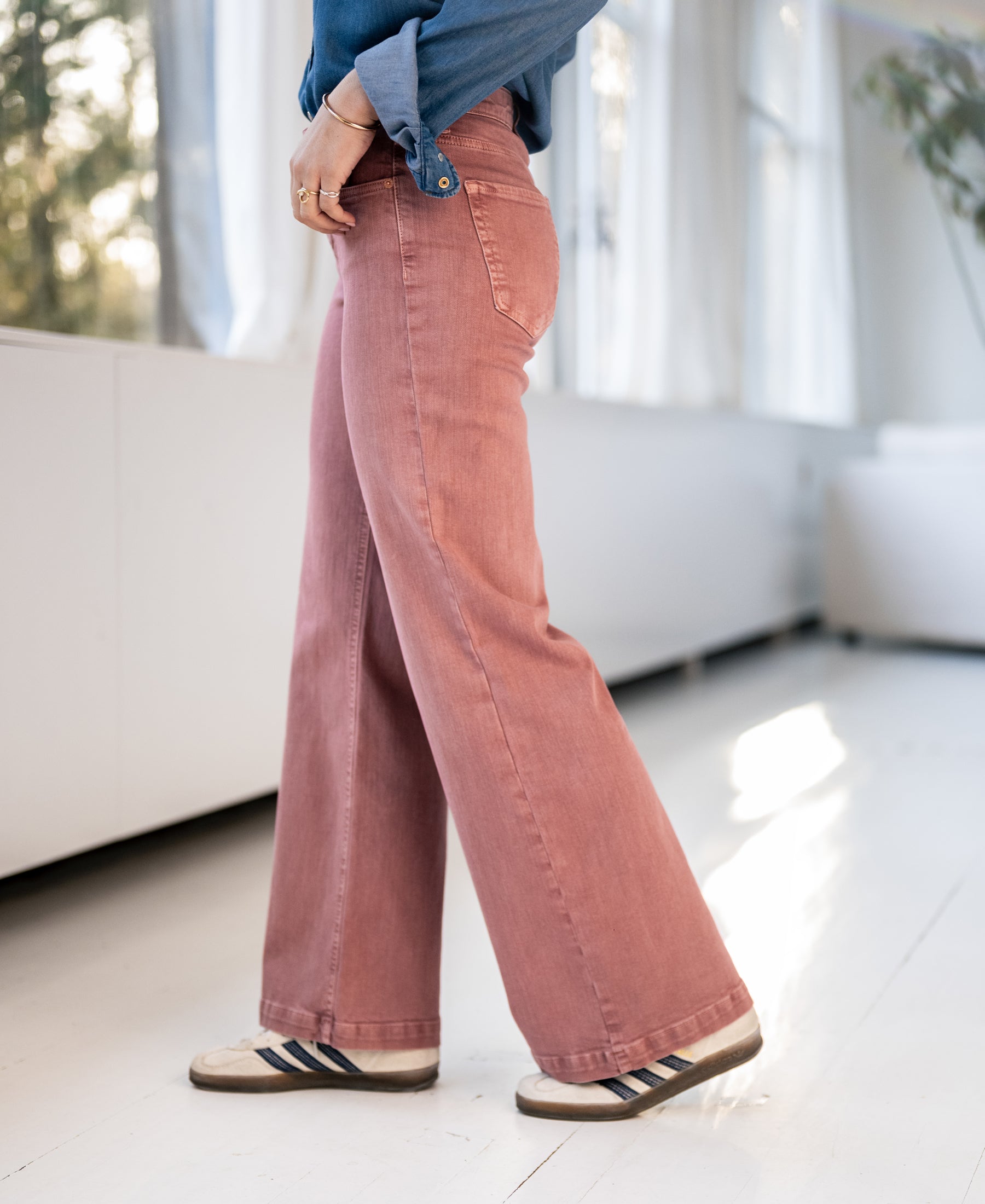 Person wears pink PLEIN PUBLIQUE jeans on a white indoor floor.
