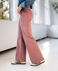 Person wears pink PLEIN PUBLIQUE jeans on a white indoor floor.