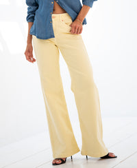 Person wearing yellow wide leg jeans standing on a white floor.