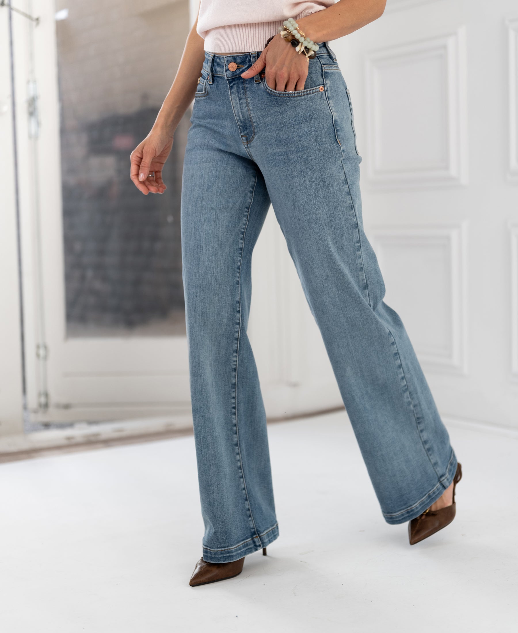 Wide leg jeans in light stone color from Les Deux, shown indoors near a white door.