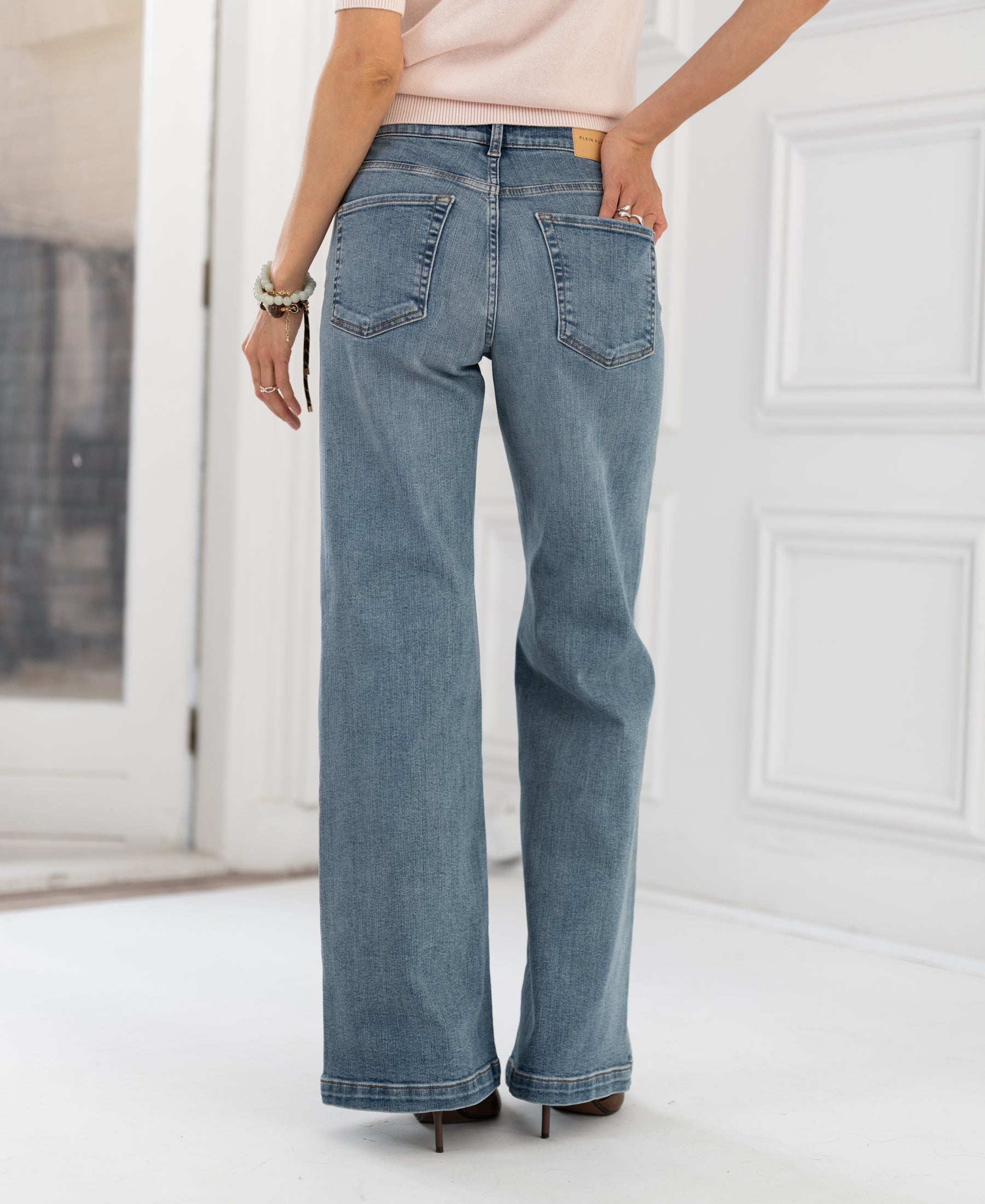 Wide leg jeans in light stone color by Les Deux, shown from the back, worn indoors.