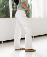 Wide leg jeans in white shown indoors near windows.
