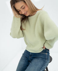 Woman wearing a light green merino wool sweater in a bright room.