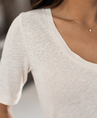 Close-up of a person wearing a cream linen T-shirt.