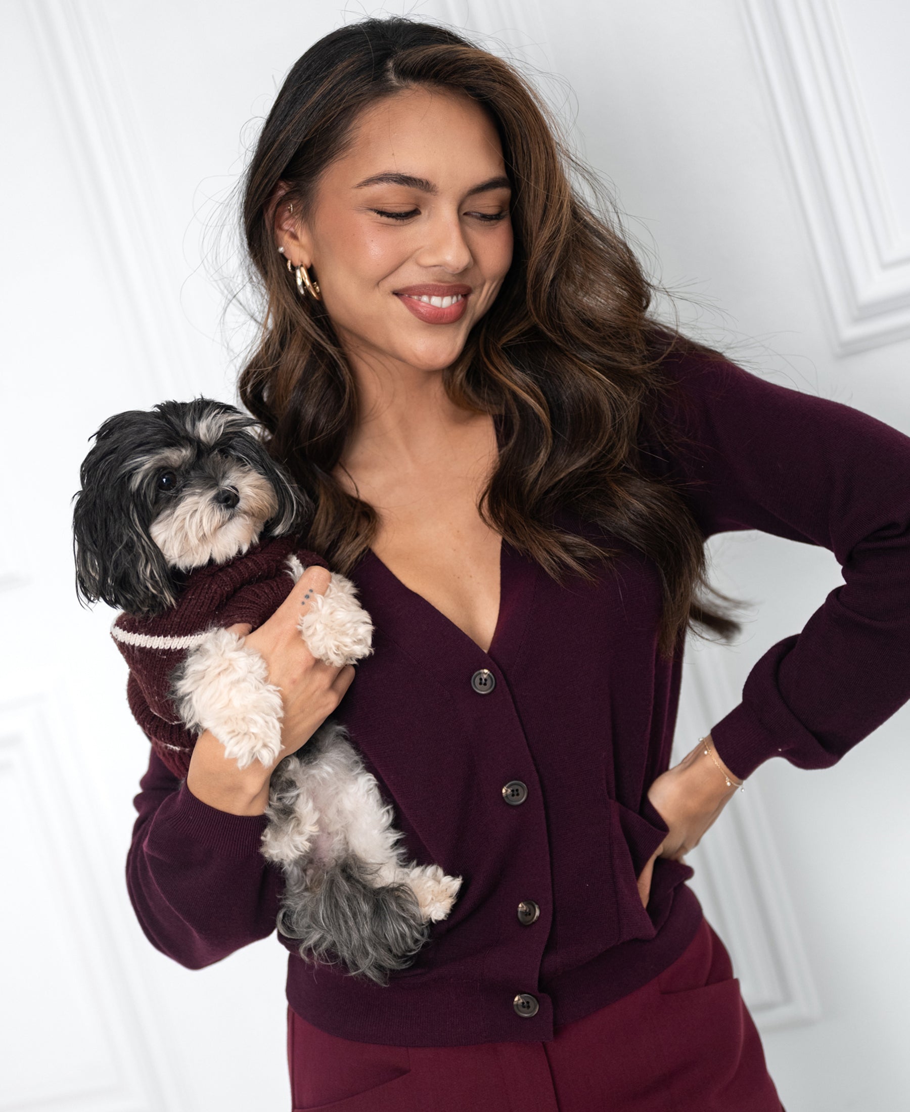 Woman wears a merino wool vest in dark cassis, smiling. The focus is on the merino vest.