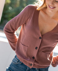 Woman wearing PLEIN PUBLIQUE Merino wool cardigan LA DONNA in dusty pink, smiling in sunlight.