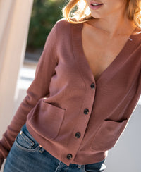 Dusty pink merino wool vest with pockets, shown in sunlight.