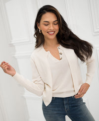 Ivory knit vest sweater by PLEIN PUBLIQUE, front view, worn by a woman standing by a white paneled wall.