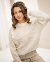 Woman wearing an ivory mohair sweater, touching her head.