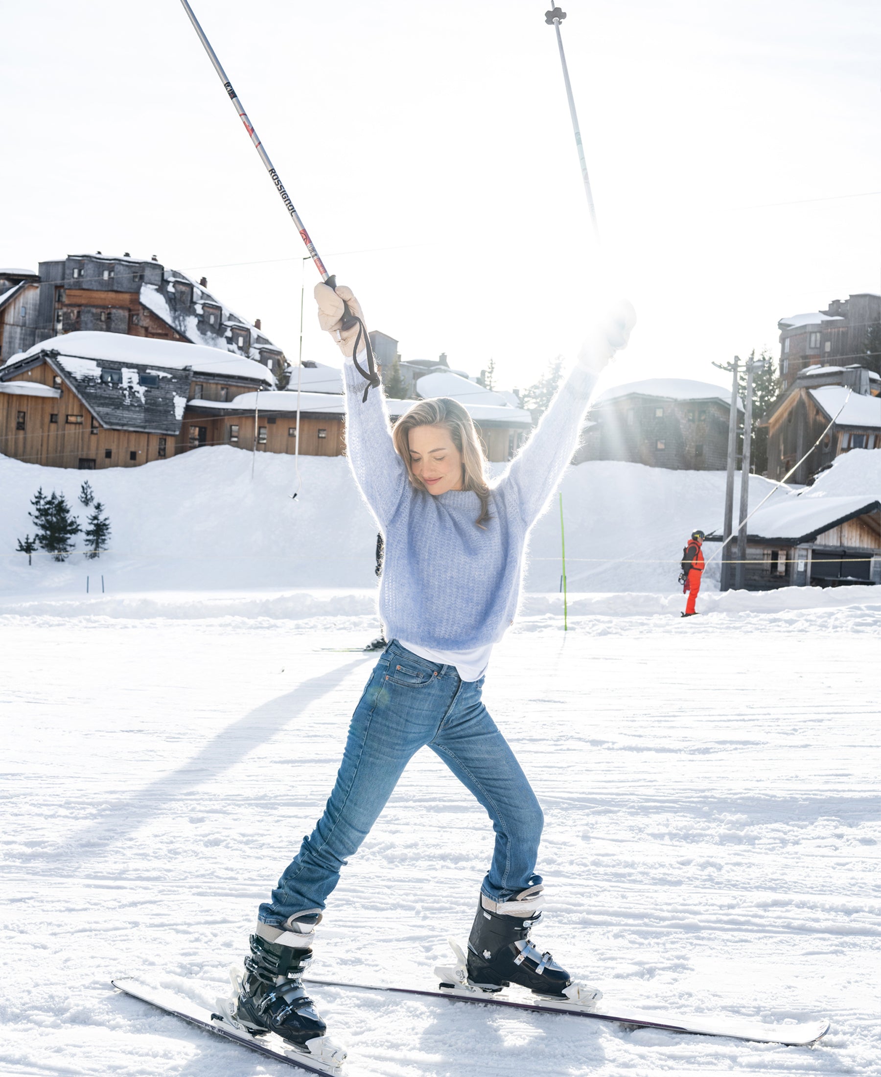 Woman wearing light blue mohair sweater outdoors, snowy cabins in background.