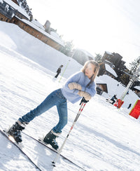 A woman wears a light blue PLEIN PUBLIQUE mohair sweater in a snowy outdoor setting.