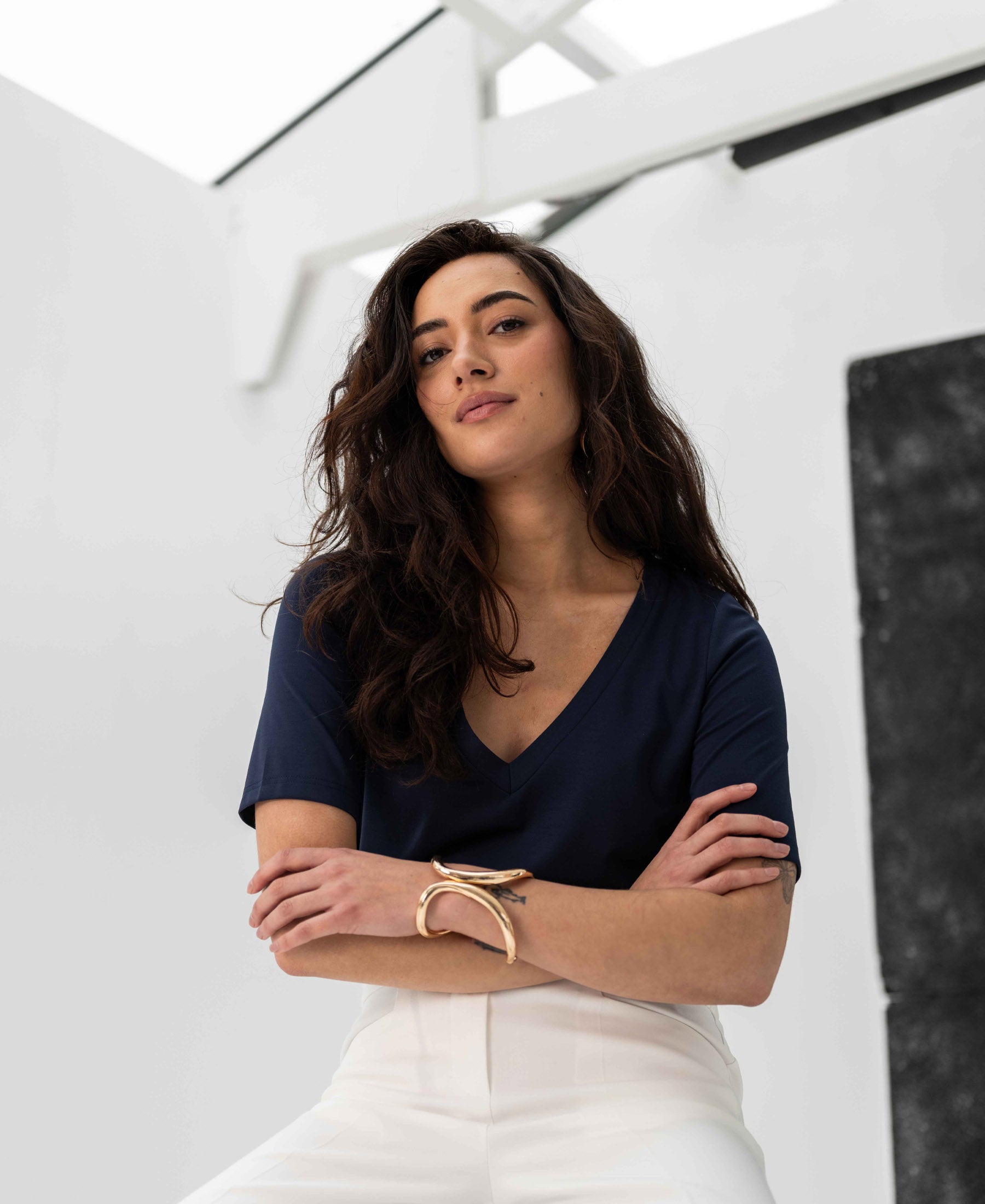 Woman wearing a PLEIN PUBLIQUE LA VERONIQUE V-neck T-shirt in dark blue, arms crossed.