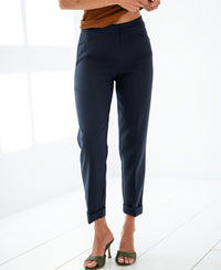 Woman wearing dark blue PLEIN PUBLIQUE 7/8 LE FAUBOURG trousers, standing on a white floor in a bright room.