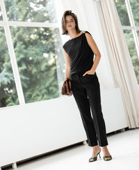 A woman wears the PLEIN PUBLIQUE black top with buckle detail.
