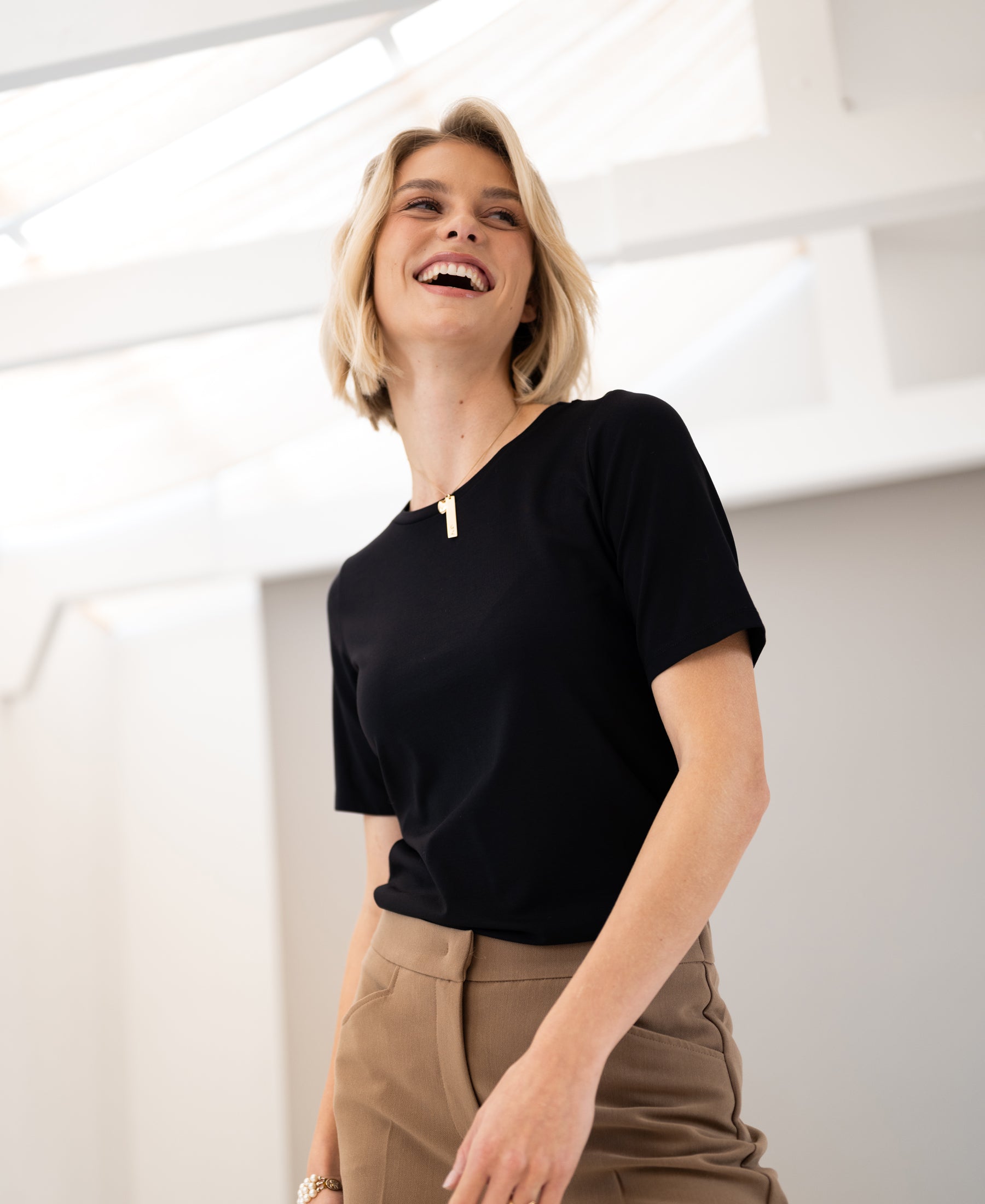 Black LE FAVORY Travel T-shirt by PLEIN PUBLIQUE shown on model standing in a bright room.