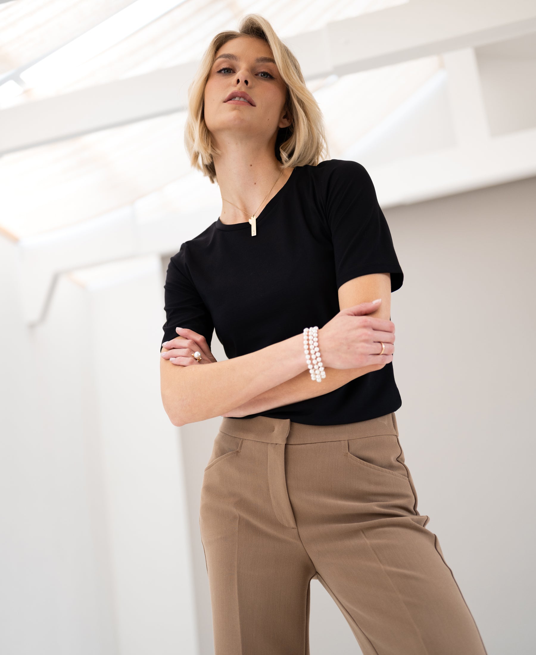 Woman wearing black PLEIN PUBLIQUE Travel T-shirt, arms crossed.