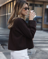 Woman wearing PLEIN PUBLIQUE’s wool jacket LA FAYE in Pure Choco color standing outdoors.