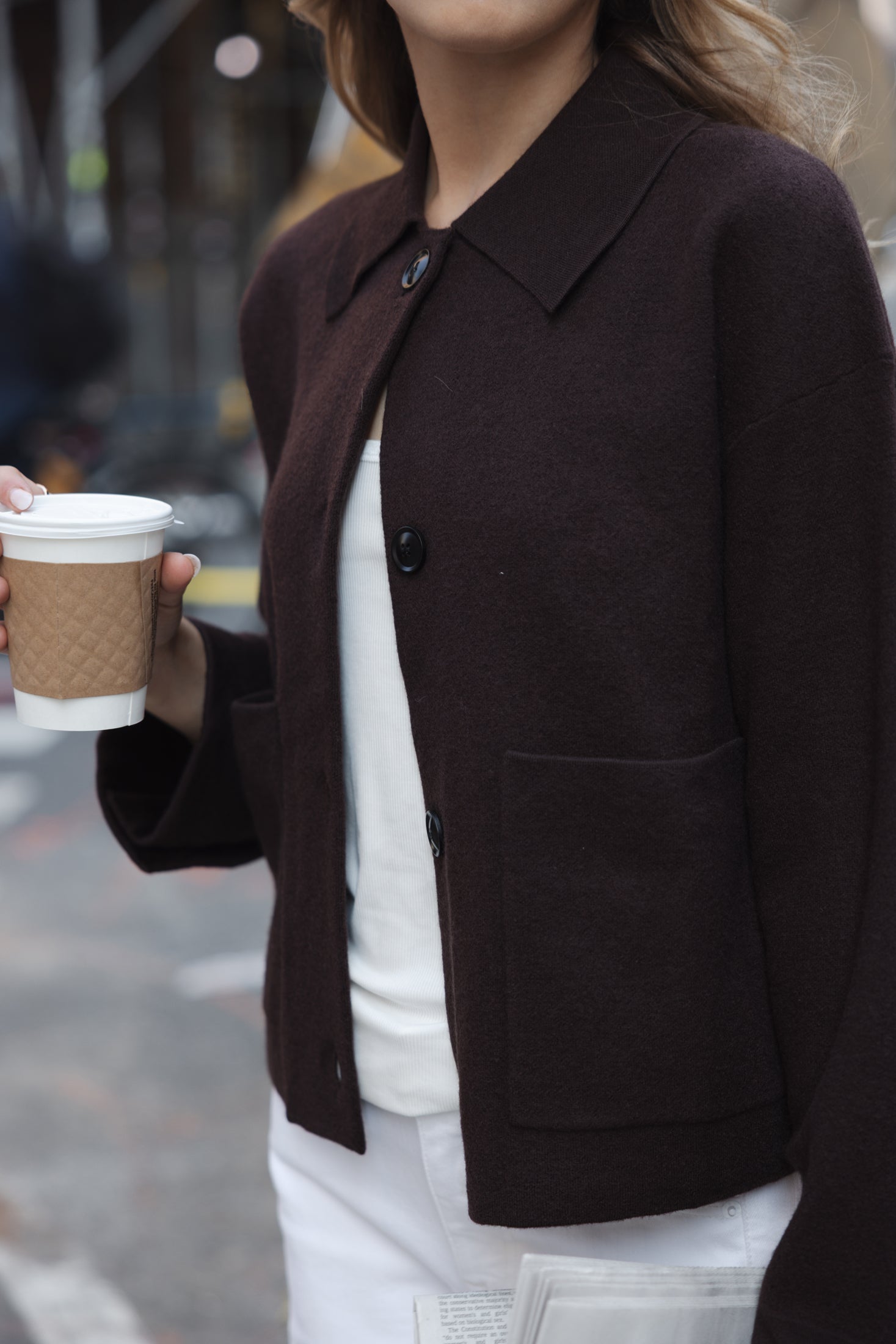 Woman wears the PLEIN PUBLIQUE wool jacket LA FAYE in Pure Choco on a city street.