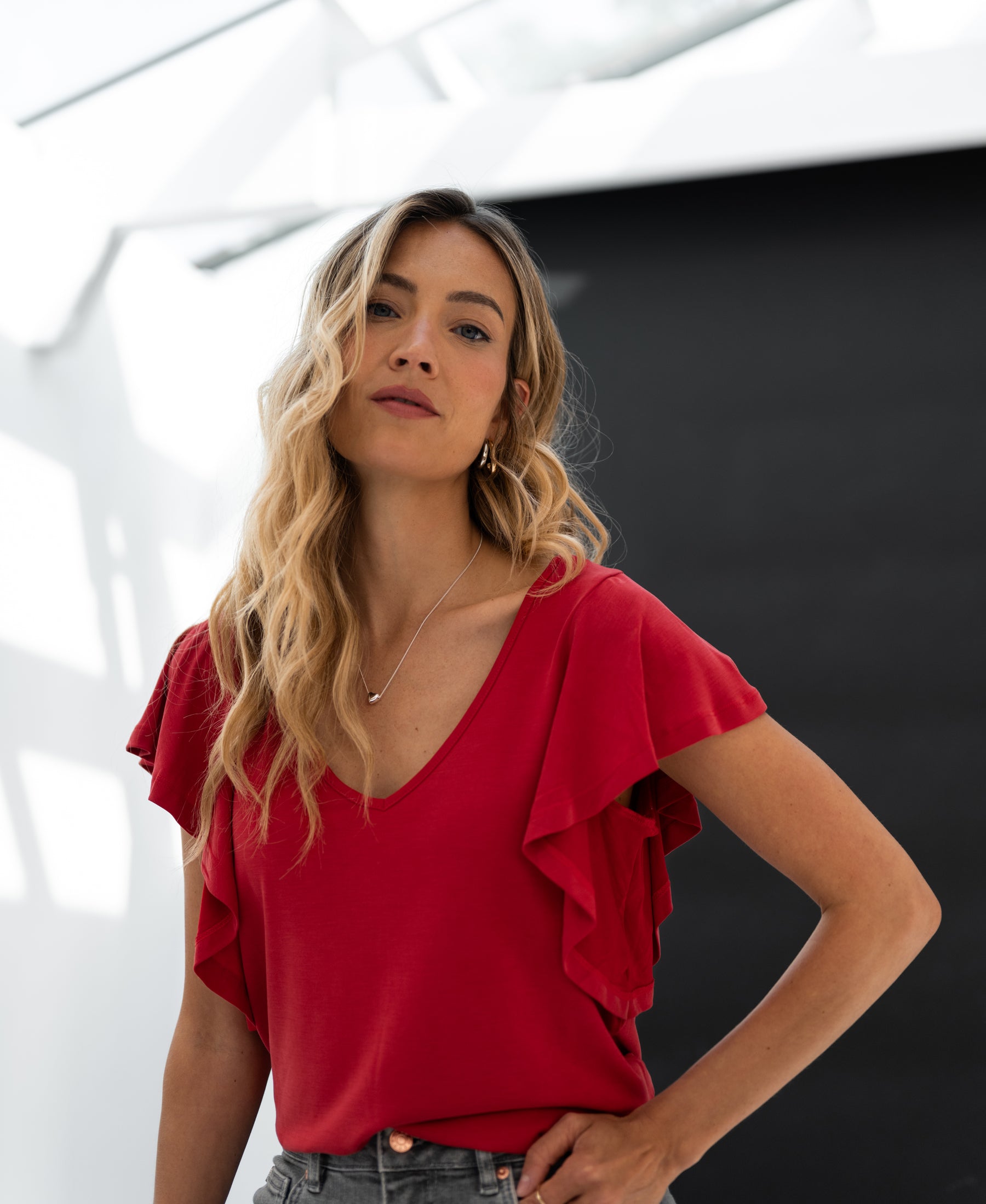 Red women's two-way top by Plein Publique, shown against a black and white backdrop.