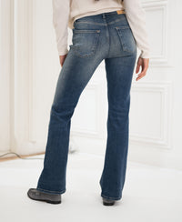 Person wearing blue vintage flare jeans, facing away indoors.