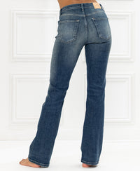 Blue vintage flared jeans, back view, shown against a white paneled wall.