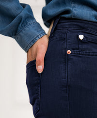 Person wearing PLEIN PUBLIQUE's LES FLARES dark blue jeans with a hand in their pocket.