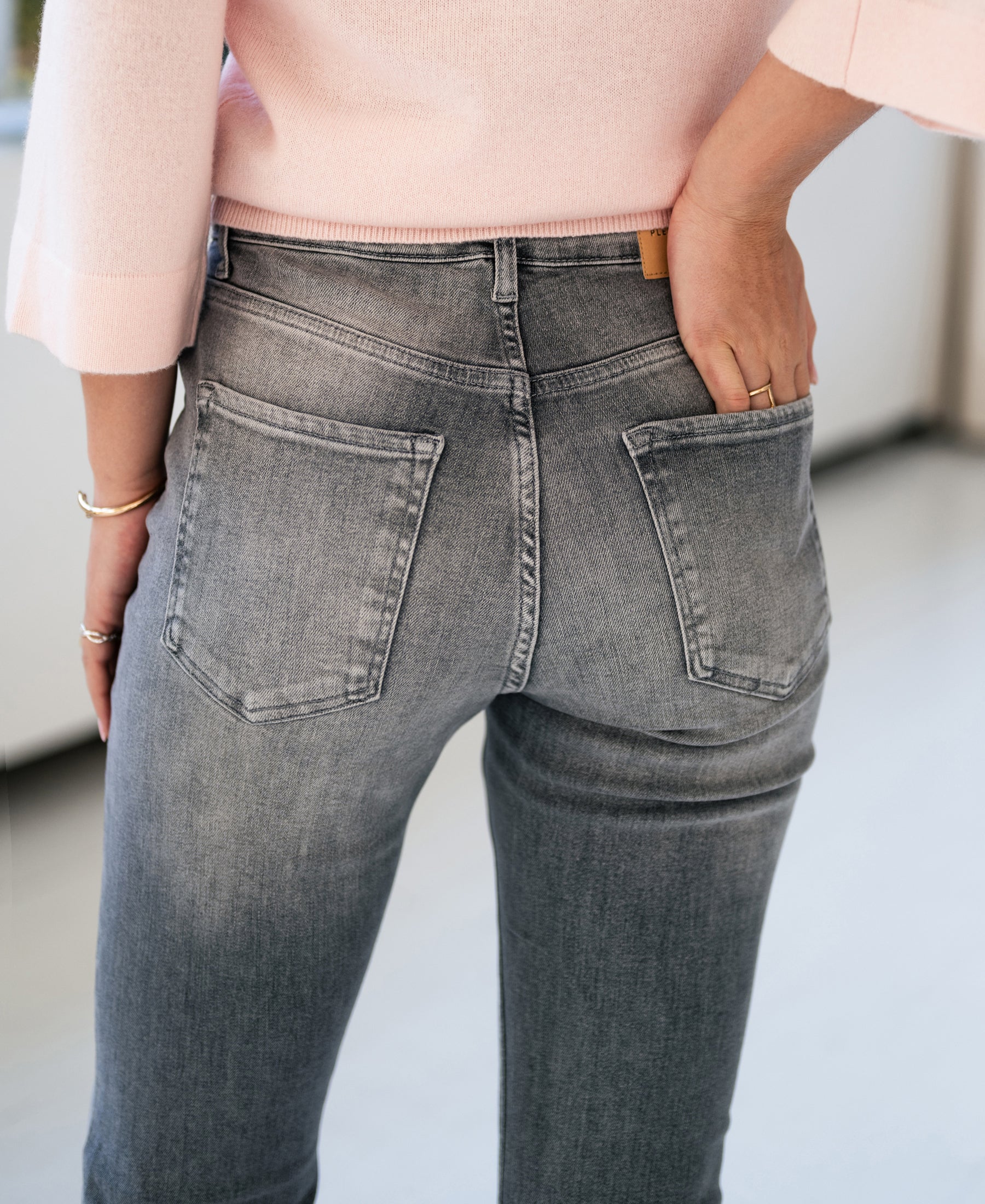 Person wearing grey stonewash flared jeans, hand in back pocket.