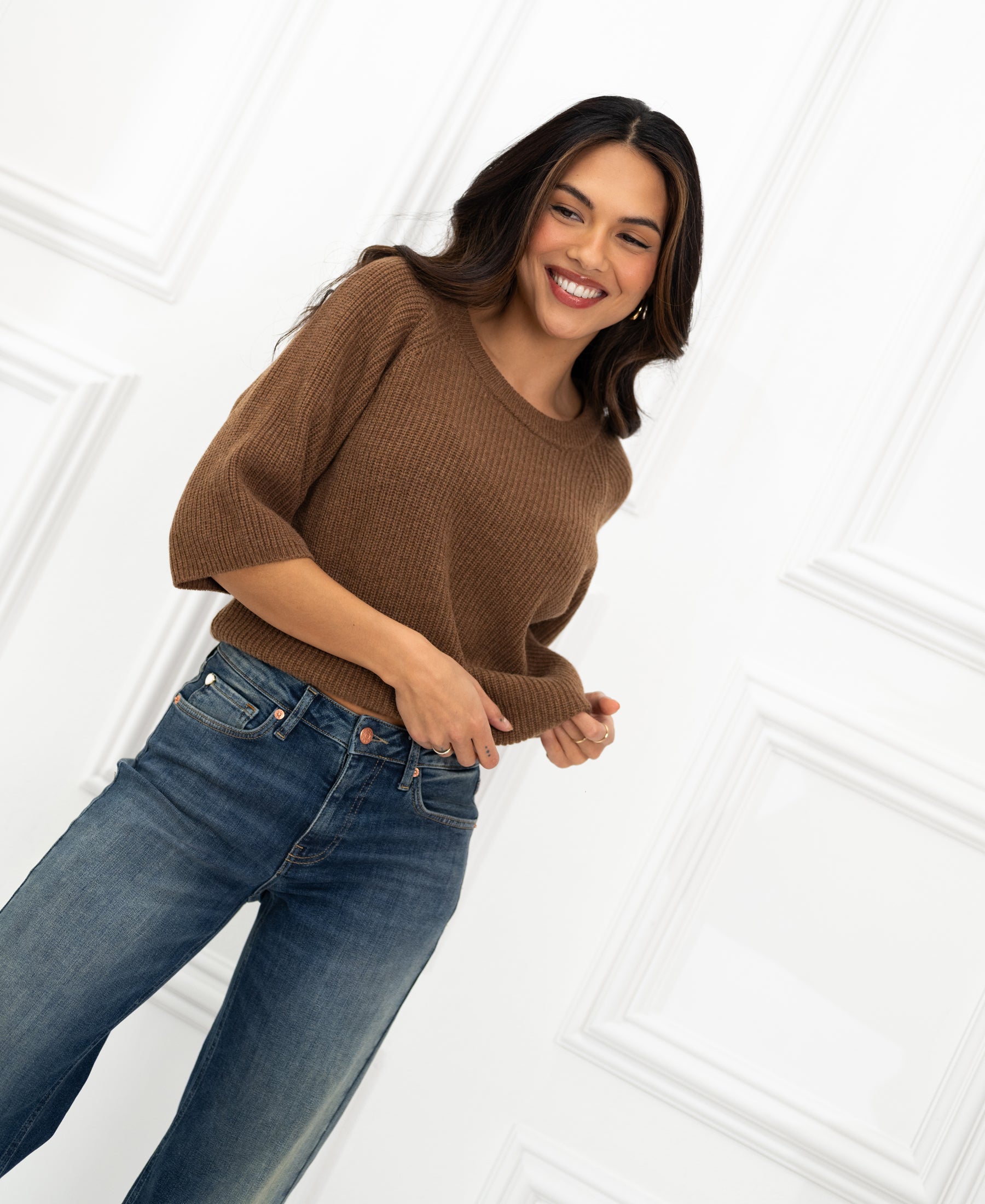 Tobacco-colored sweater by PLEIN PUBLIQUE shown on model standing by a white paneled wall.