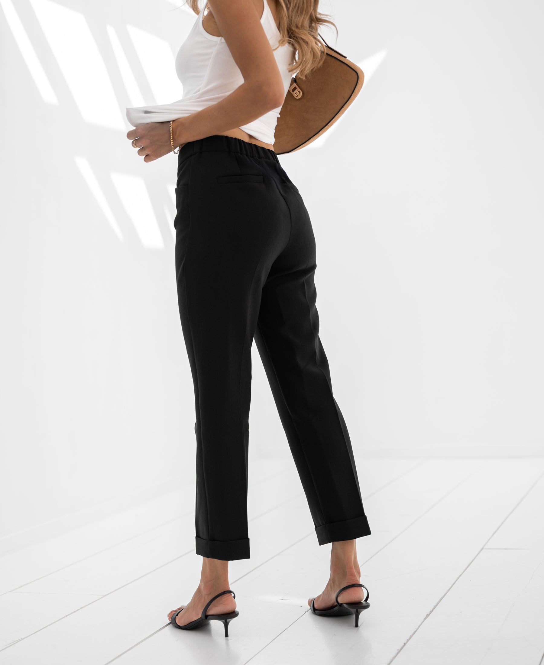 Woman wearing black 7/8-length trousers.