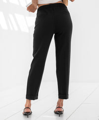 Black cropped pants seen from behind on a white floor.