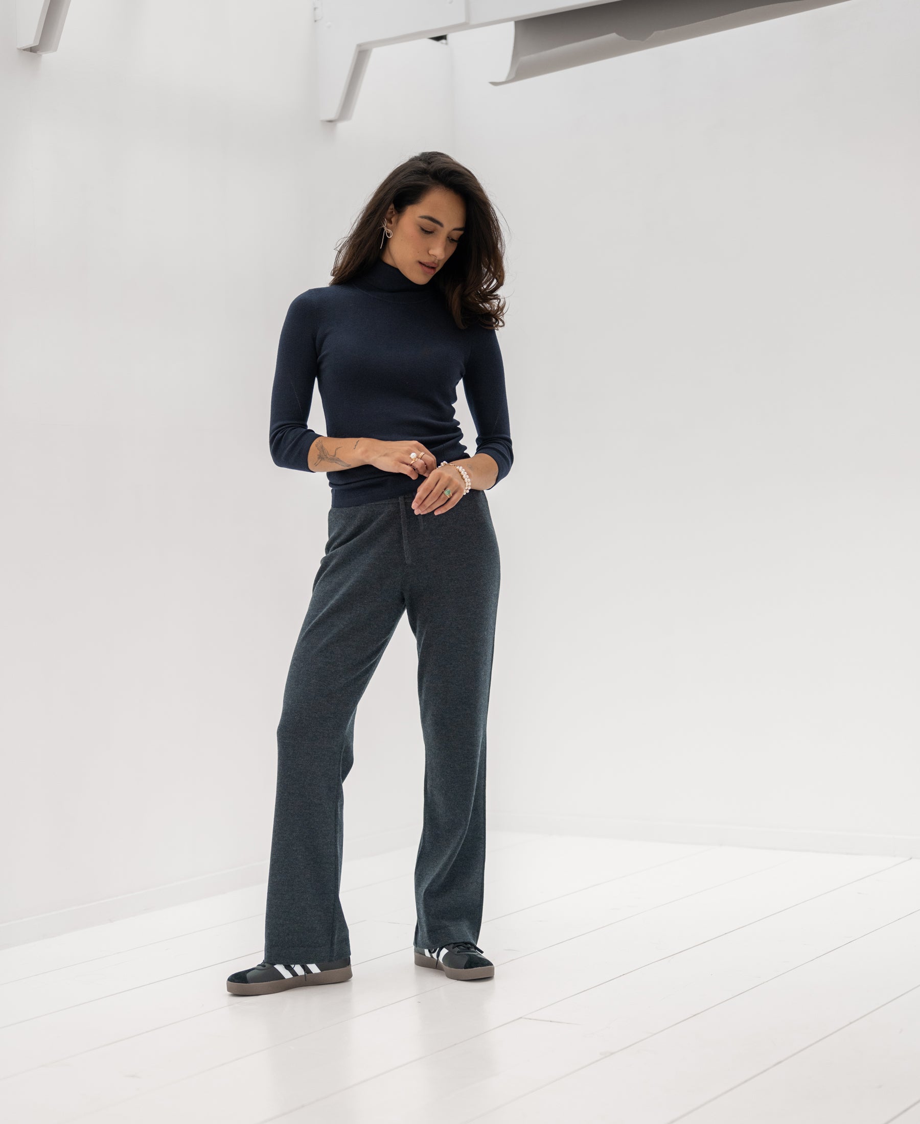 Woman wearing the LE FABIAN Dark Blue Turtleneck Sweater by PLEIN PUBLIQUE in a bright, minimal room.