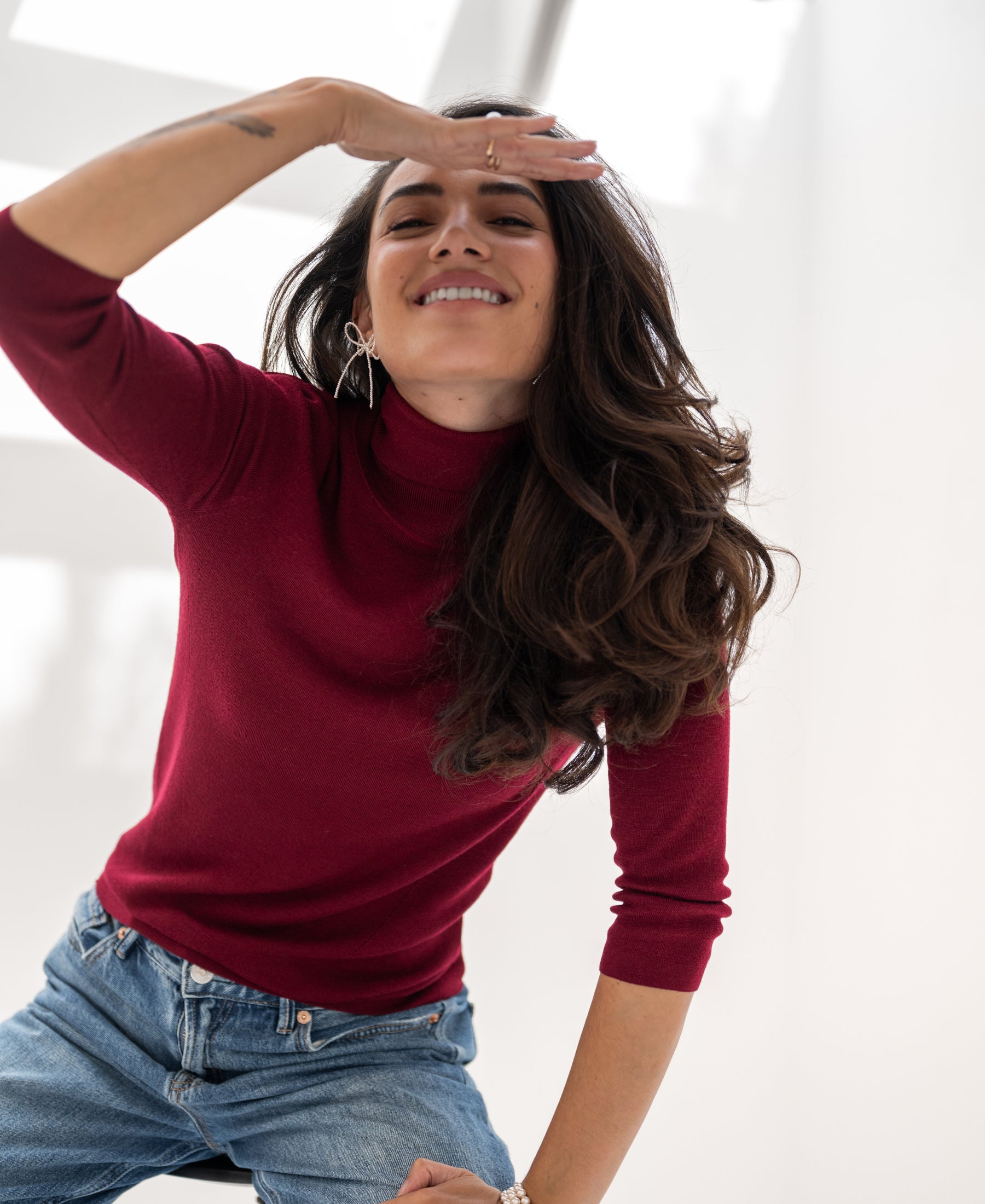 Woman wearing a PLEIN PUBLIQUE LE FABIAN dark red turtleneck.
