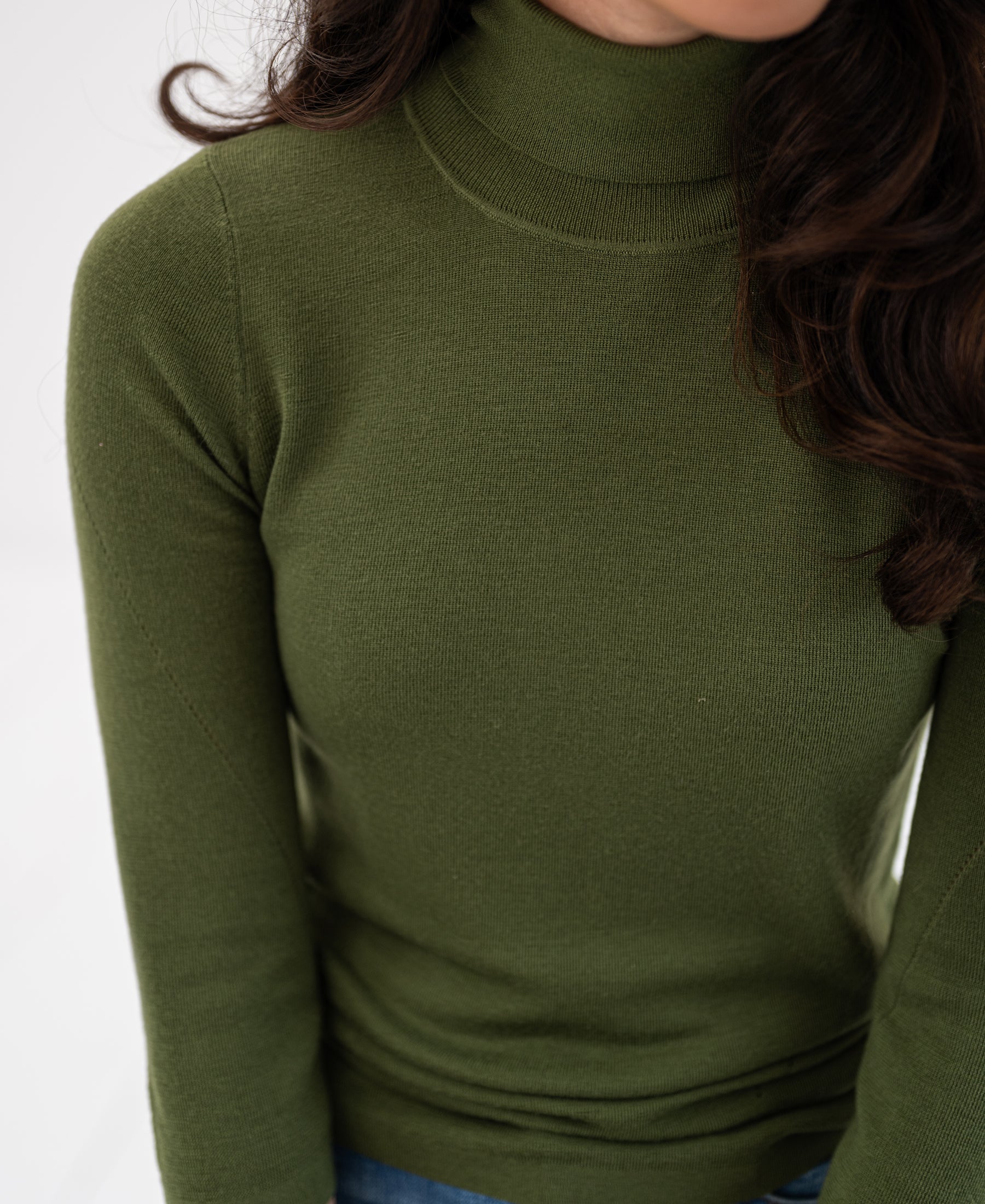 Olive green turtleneck sweater in view from shoulders down.