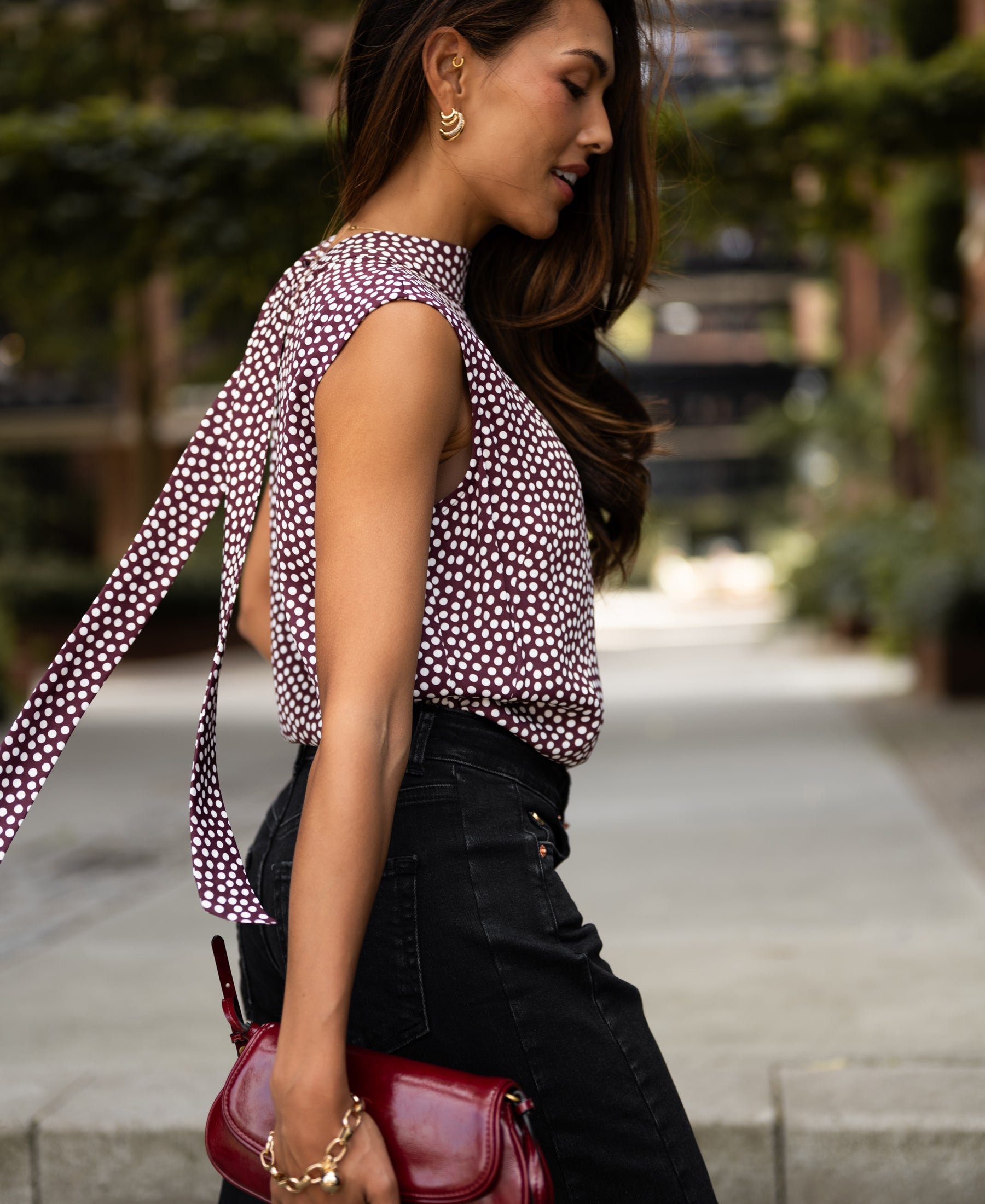 Woman wearing PLEIN PUBLIQUE Polka Dot Blouse Top LA GIVERNY Wine-Ivory standing outdoors on a sunny day.