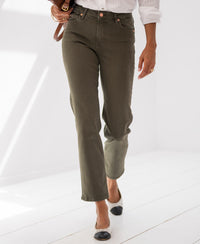 Person wearing army green cropped jeans, photographed indoors on a white floor.