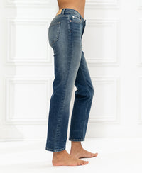Cropped blue vintage LE GUY jeans shown in profile view against a white decorative panel wall.
