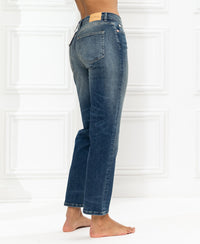 Cropped LE GUY blue vintage jeans with straight legs, shown from the side and back against a white textured wall.