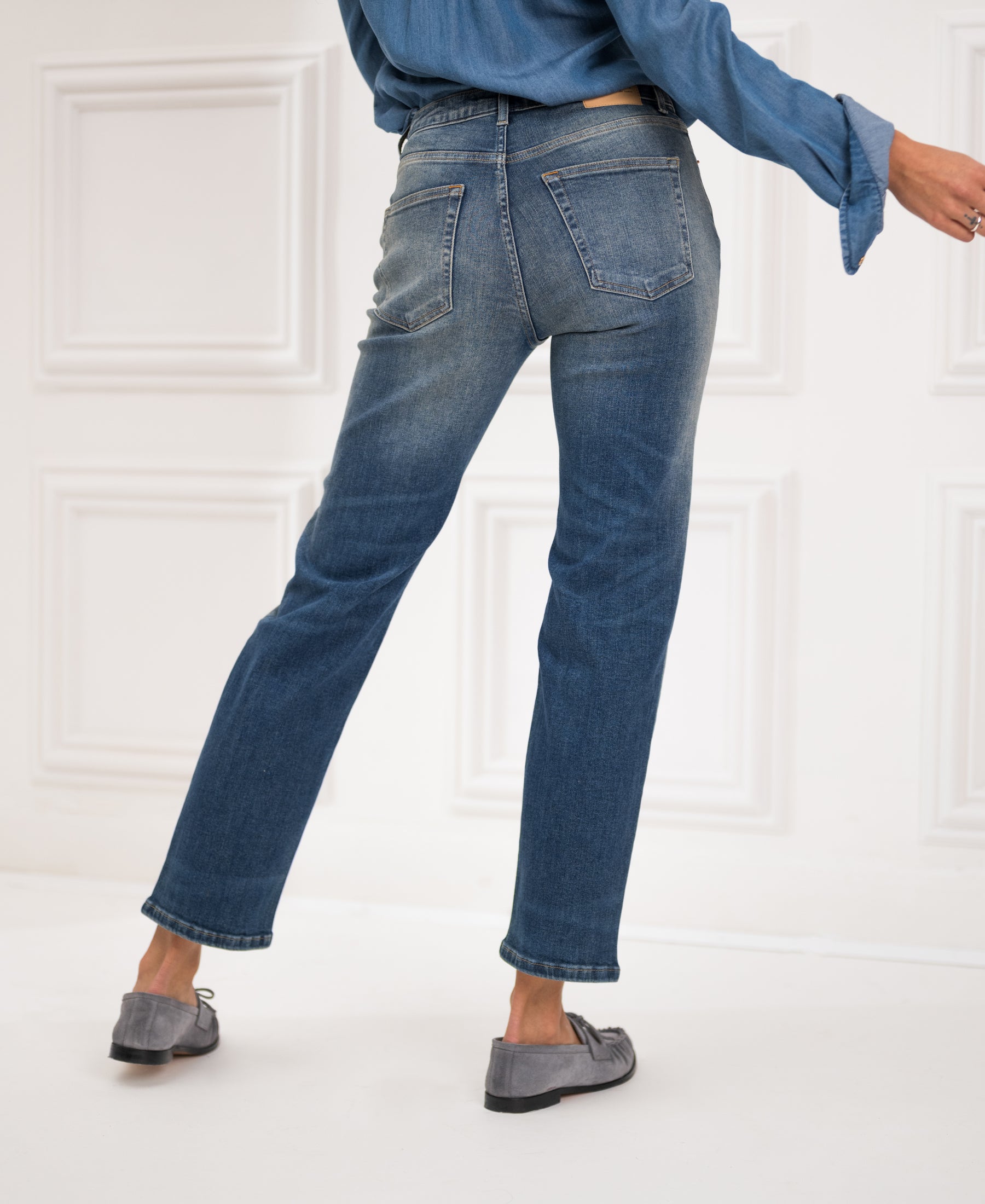 Person wearing blue vintage cropped jeans, one leg bent.