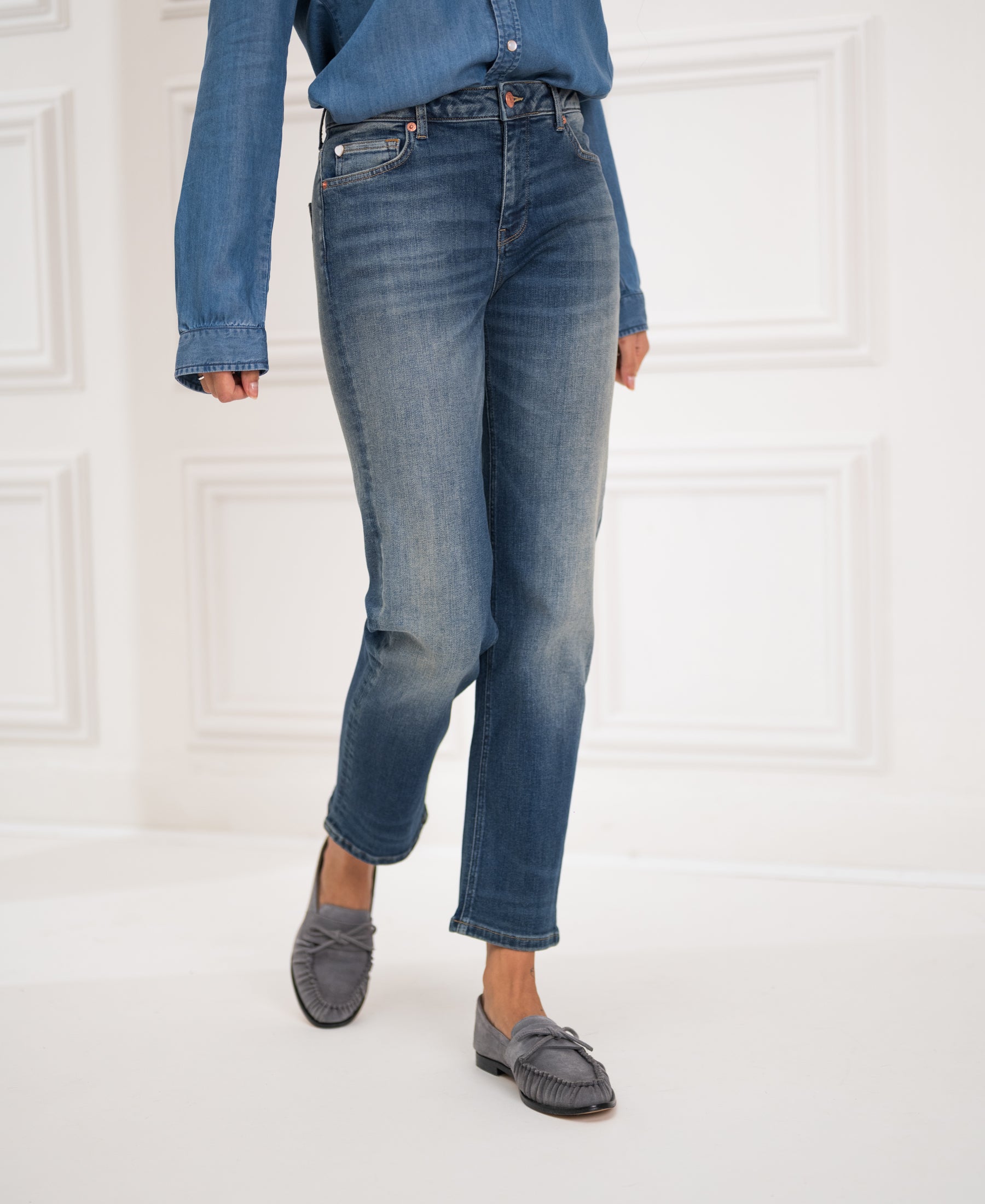 Person wears blue vintage cropped jeans called LE GUY in a bright room with white walls.