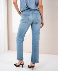 Back view of cropped light stone-wash jeans by PLEIN PUBLIQUE, shown in a bright room.