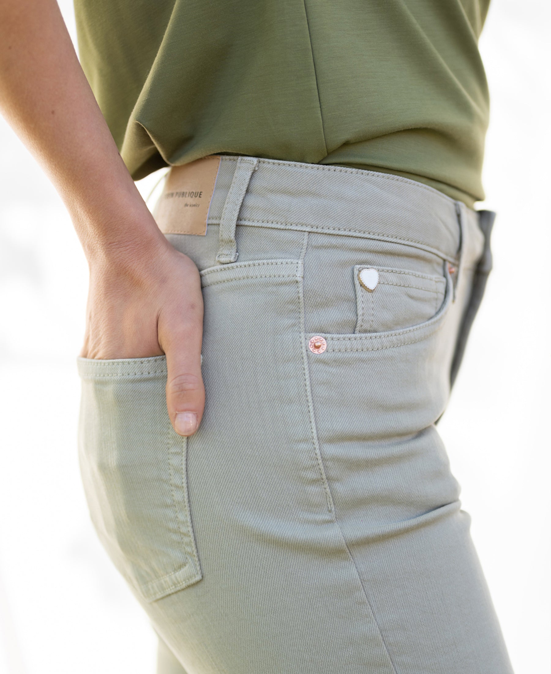 Green cropped jeans with a hand in the front pocket.