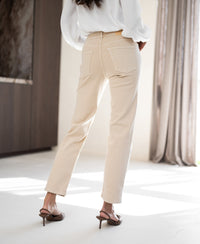 Cropped jeans in sand color by Plein Publique, shown indoors with sunlight streaming in.