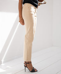 Person wears sand-colored cropped jeans in a sunlit room.