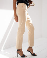 Woman wearing light beige cropped jeans, standing against a light background.