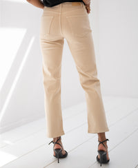 Beige cropped jeans by Plein Publique displayed on a white floor in a bright room.