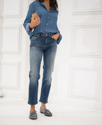 Cropped blue vintage jeans, shown worn by a woman standing against a white paneled wall.
